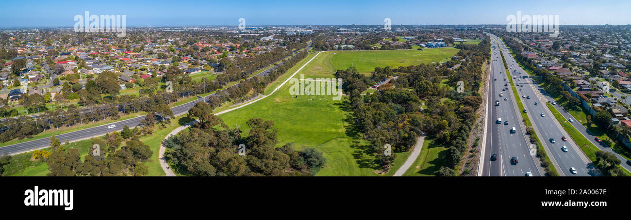 Aerial panoramic landscape of cars driving on highway passing through typical suburban landscape in Melbourne, Australia Stock Photo
