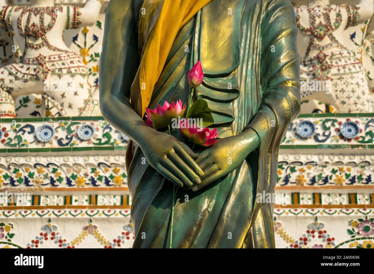 Standing Buddha sculpture wrapped in golden robe, kasaya, with lotus ...