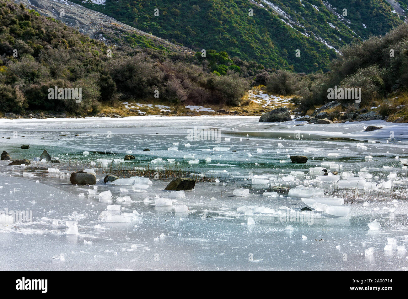 Ice pieces of frozen lake against wintry mountain background. Blue lakes, South Island, New Zealand. Stunning icy scenery landscape Stock Photo