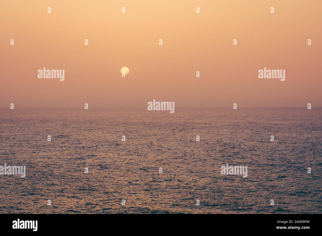 sunset on water, sun going down behind ocean - Stock Photo