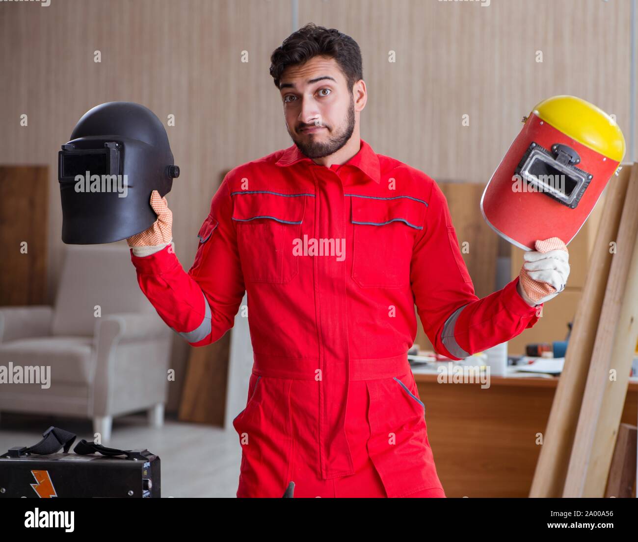 Young repairman with a welding gun electrode and a helmet welding metal