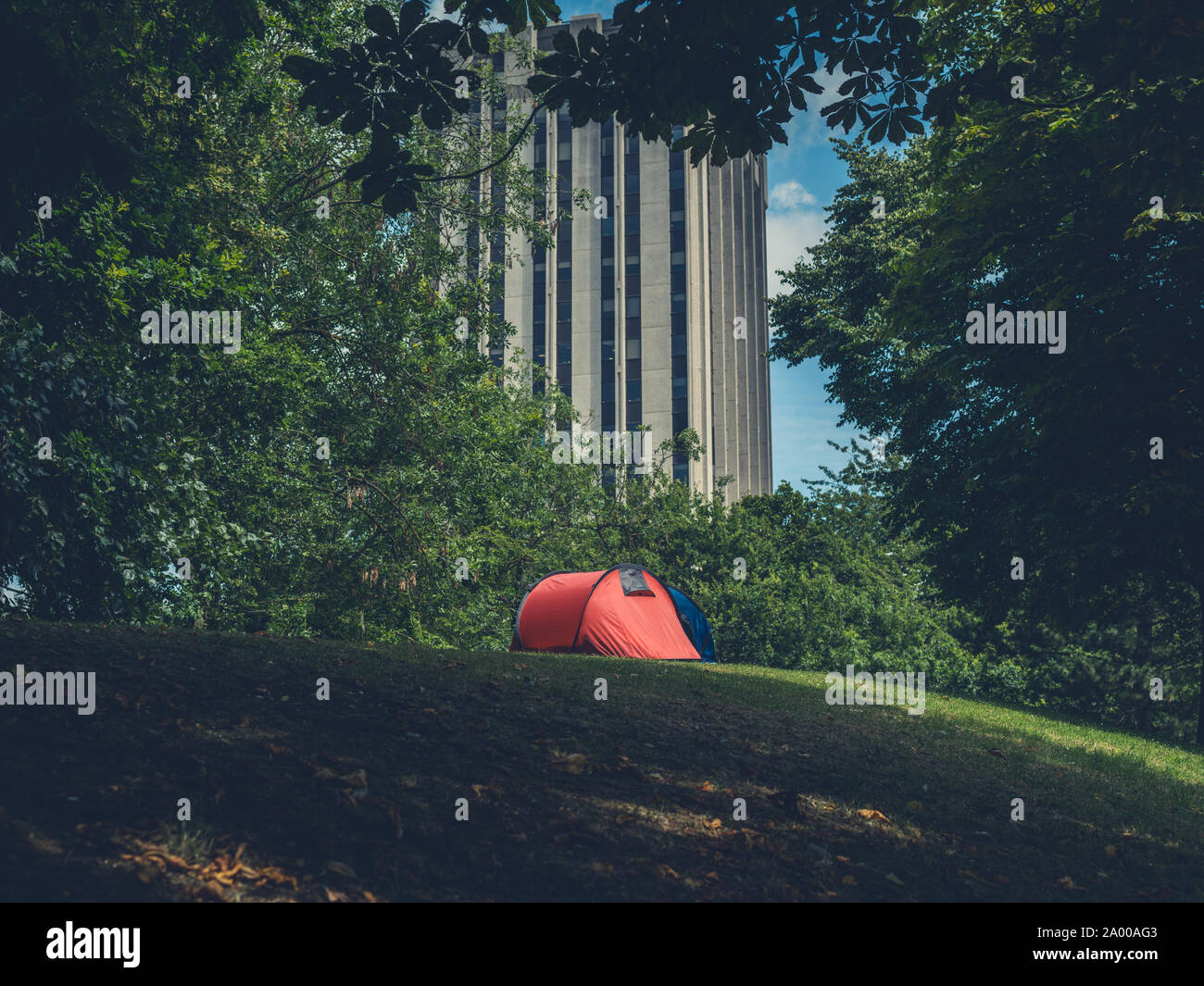 Two tents pitched in a city park with a skyscraper in the background Stock Photo