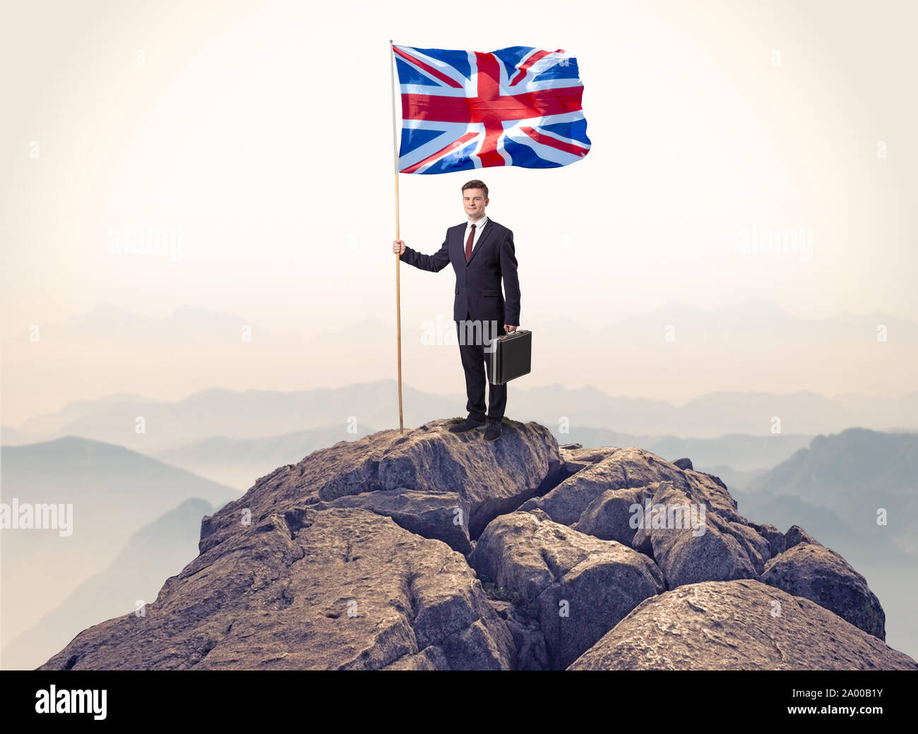 Successful businessman on the top of a mountain holding victory flag ...