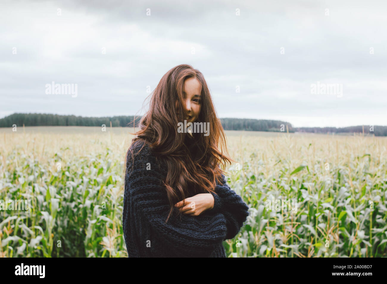Beautiful carefree long hair asian girl in knitted sweater in autumn corn field. Sensitivity to nature concept Stock Photo