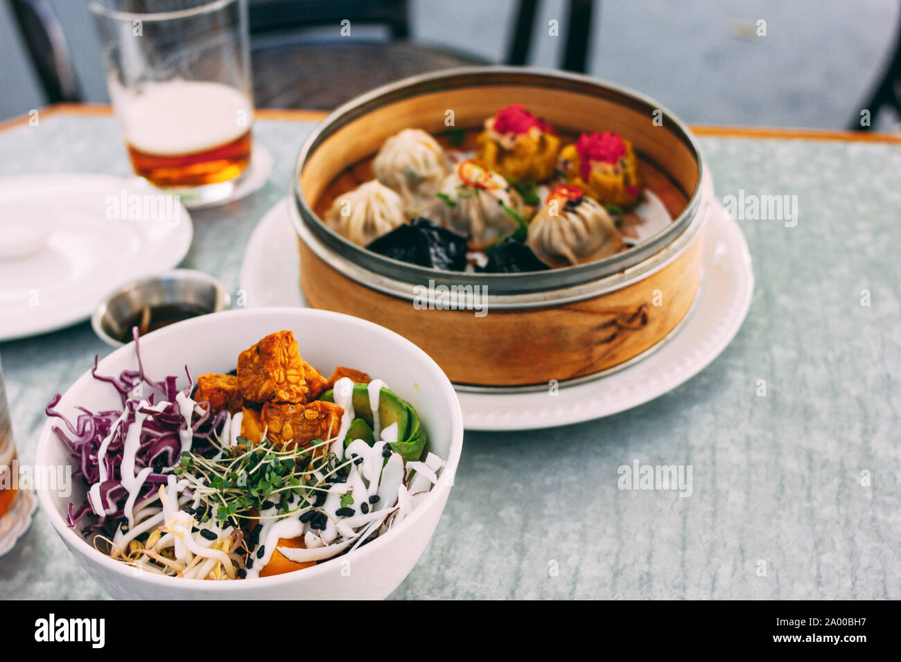 Pan-Asian food - vegetable salad bowl and different dim sums. Lunch for two with beer Stock Photo