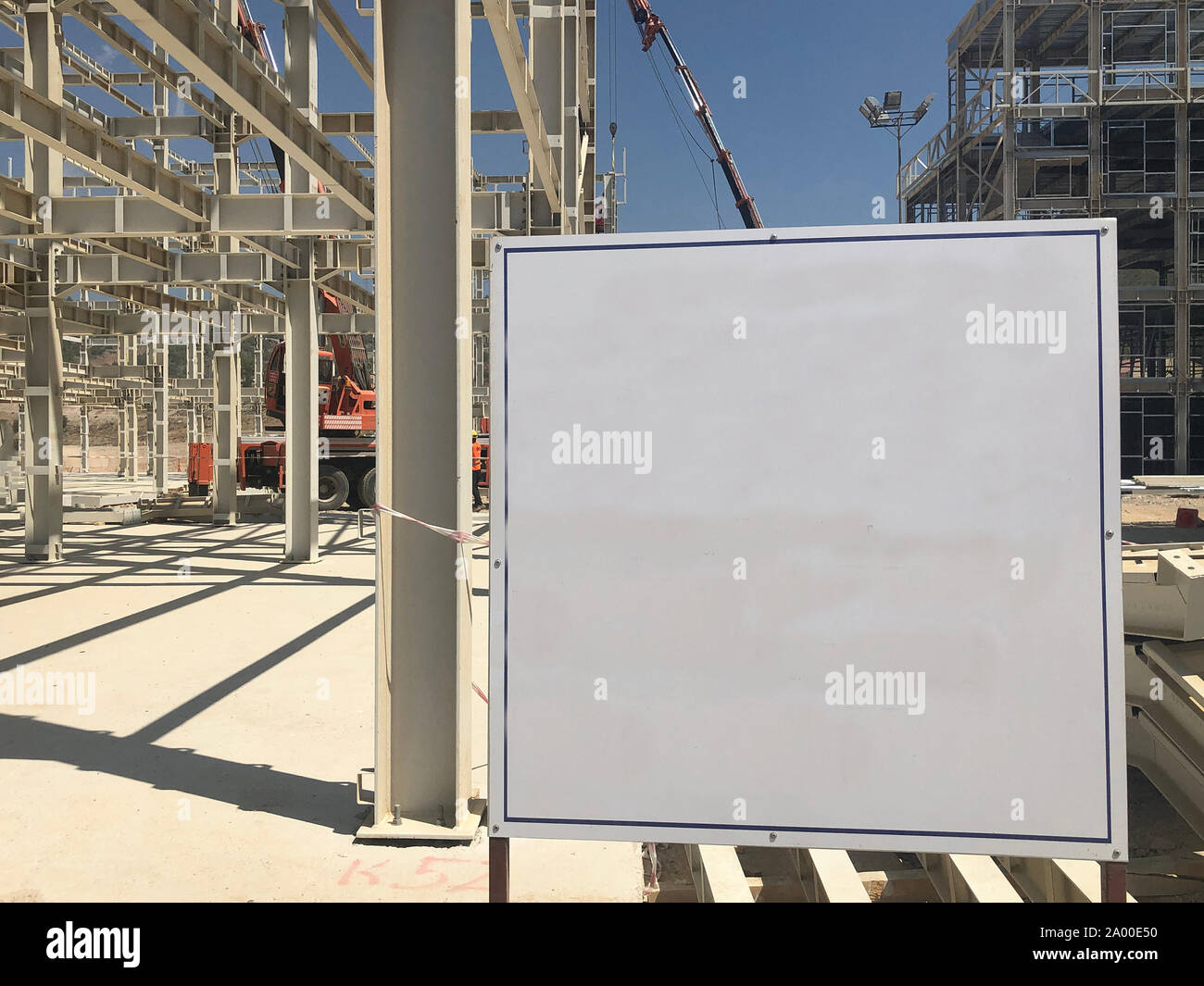 Object under construction stand at the construction site. Blank display board against prefabricated multi-storey building at the background Stock Photo