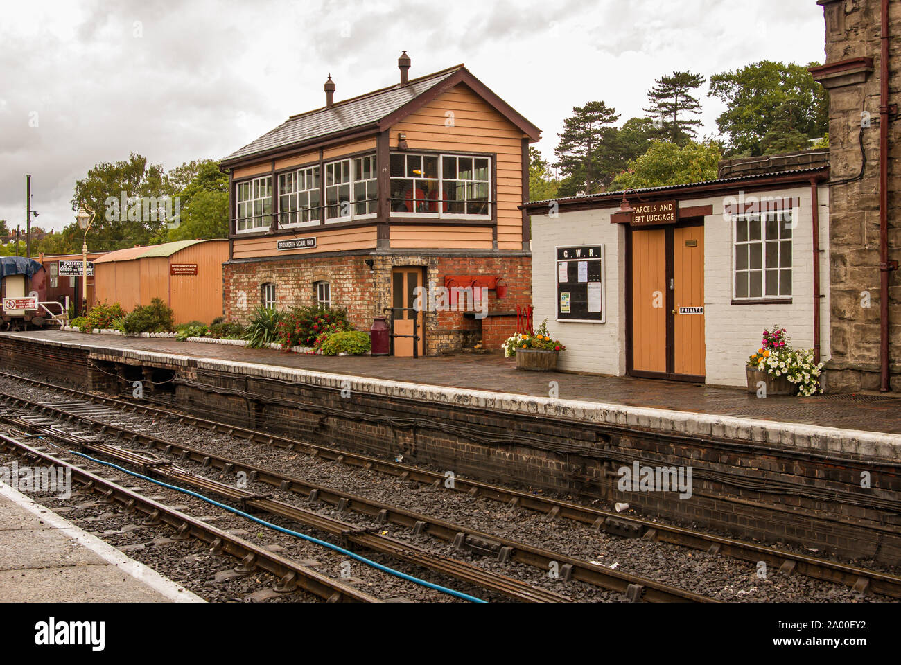 Old signal box on platform of railway station with train tracks in foreground Stock Photo