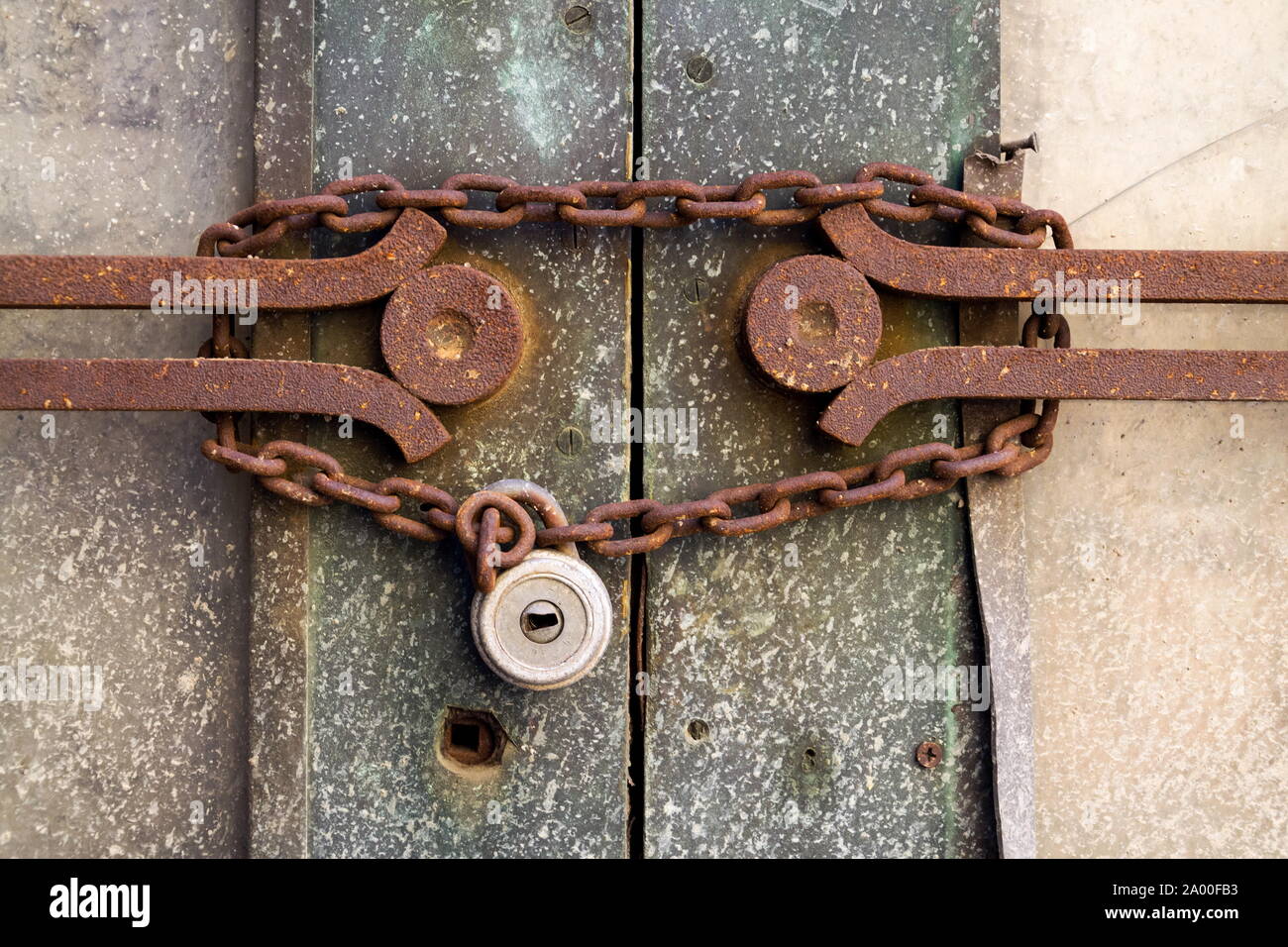 Old metallic padlock with rusty vintage chain hangs on old door, security concept Stock Photo