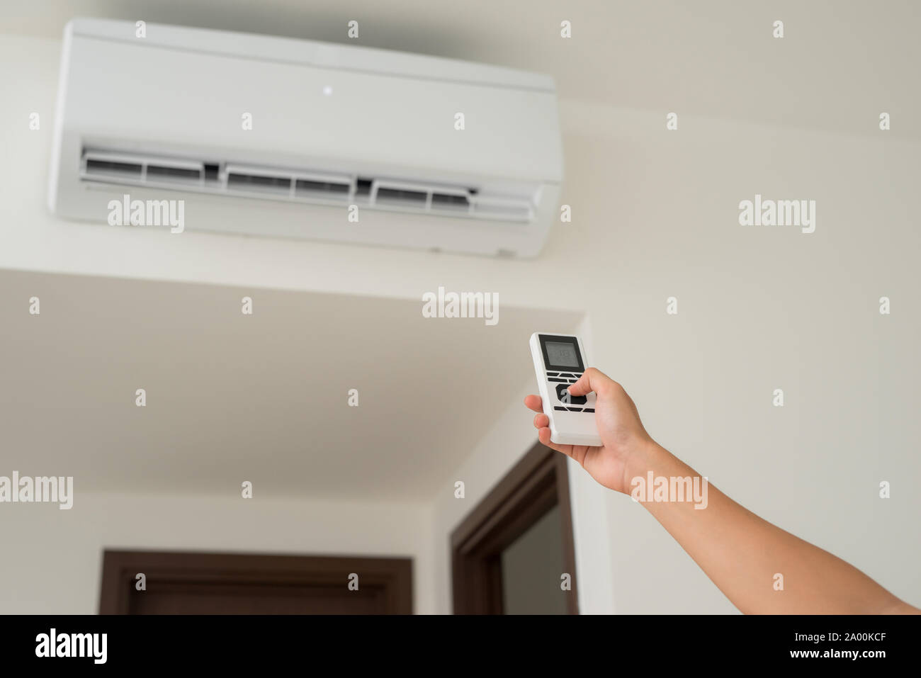 Air conditioner inside unit with man operating remote controller. / Air