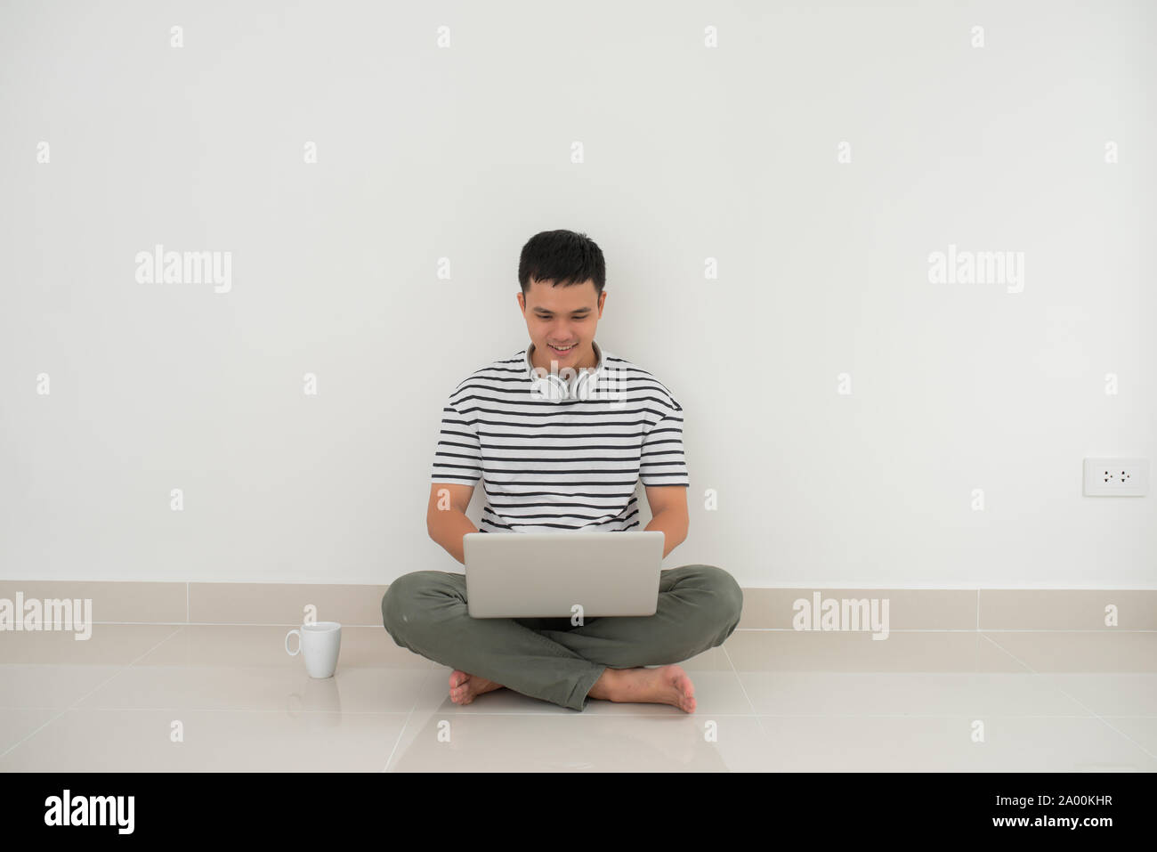 Man sitting on the floor with laptop computer in studio. Isolated white ...