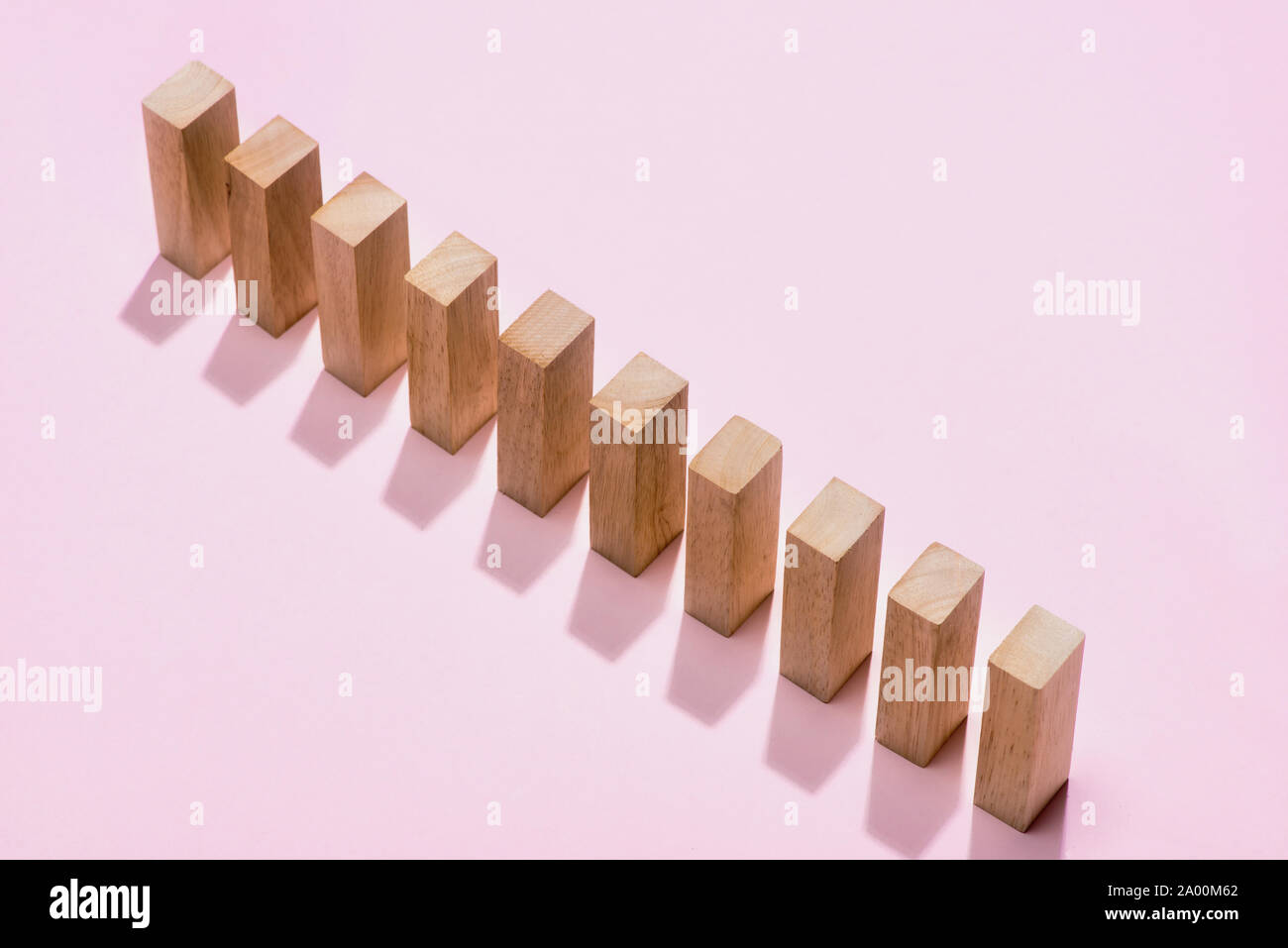 Domino block. Dominoes continuous toppled on pink background. Stock Photo