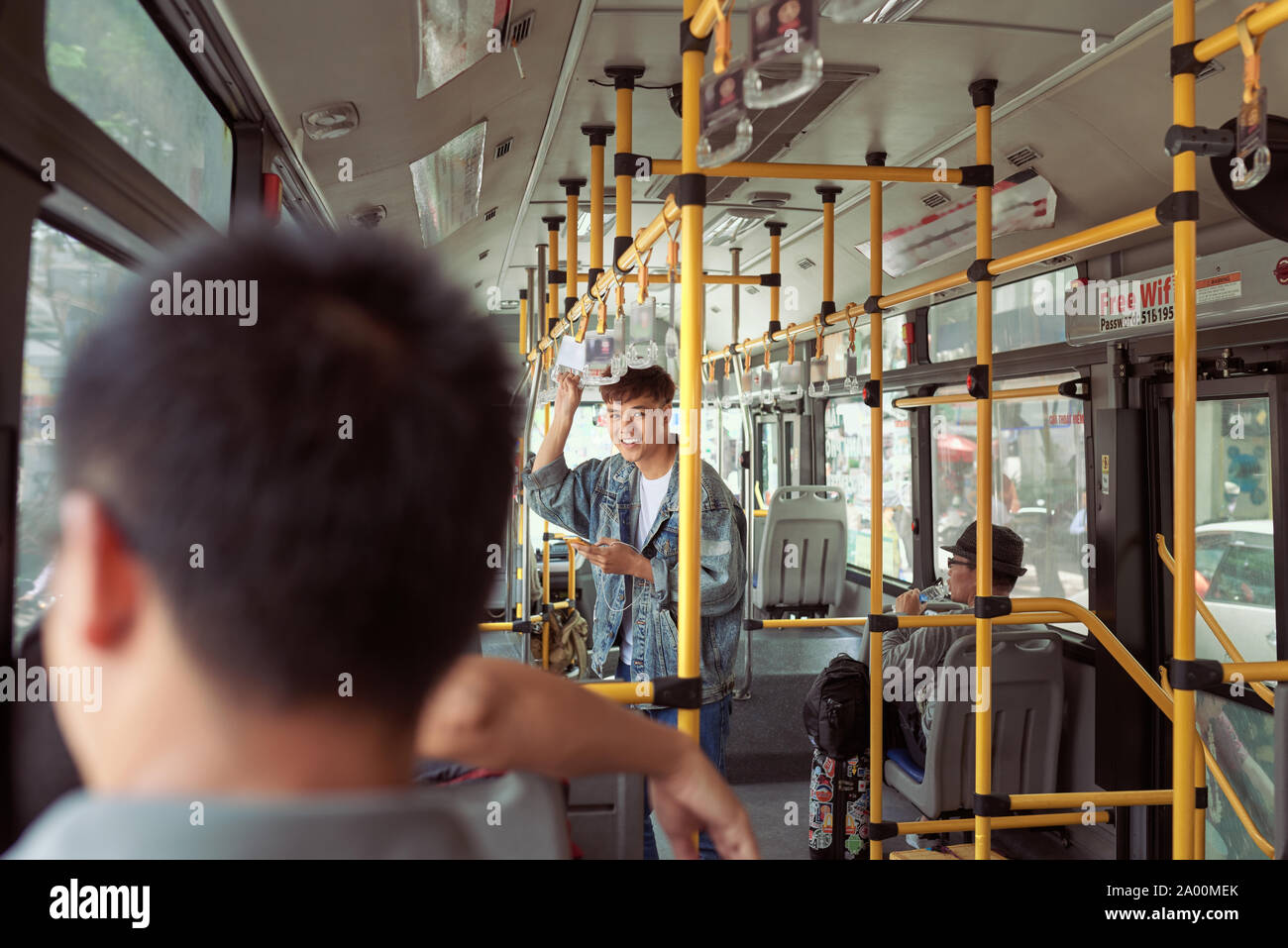 HO CHI MINH CITY, VIETNAM - 22 JULY, 2017: Transport: handsome young man in a blue denim jacket using smartphone in bus Stock Photo