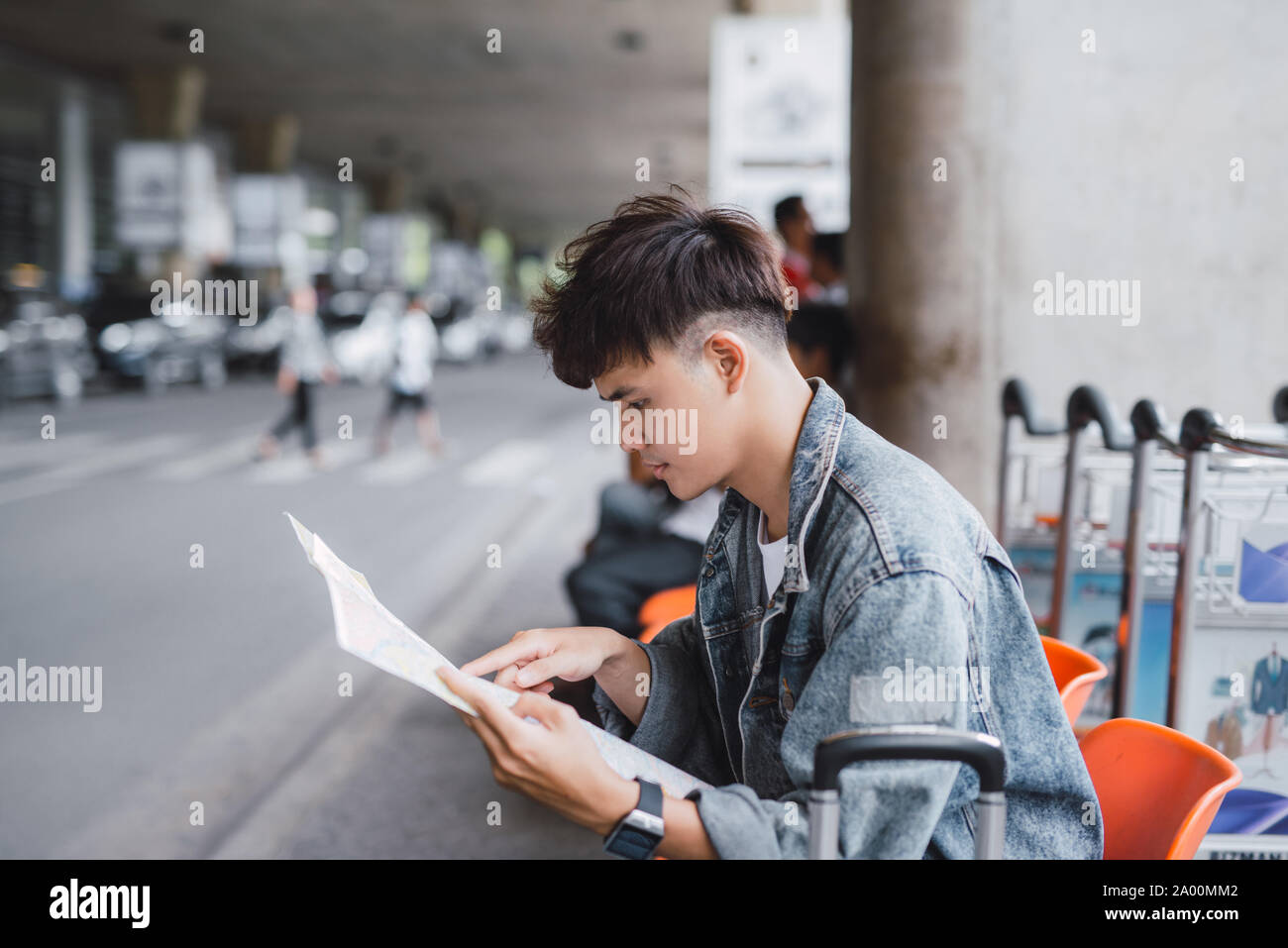 Young man handsome with luggage bag on city street with busy traffic transport looking map, waiting for public bus Stock Photo