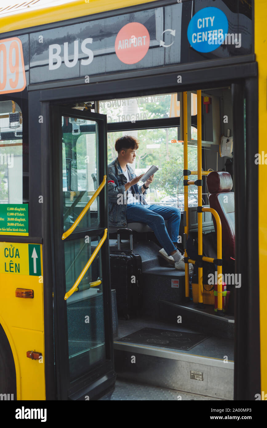 HO CHI MINH CITY, VIETNAM - 22 JULY, 2017: Asian male tourist sitting in city bus and reading a map.Asian male tourist sitting in city bus and reading Stock Photo
