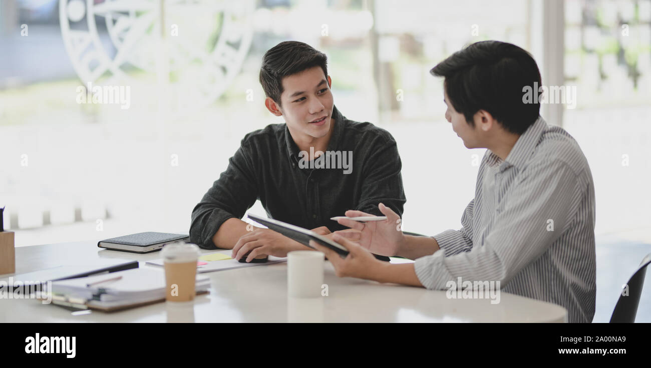 Two professional businessmen discussing their progress of their current project while using tablet Stock Photo