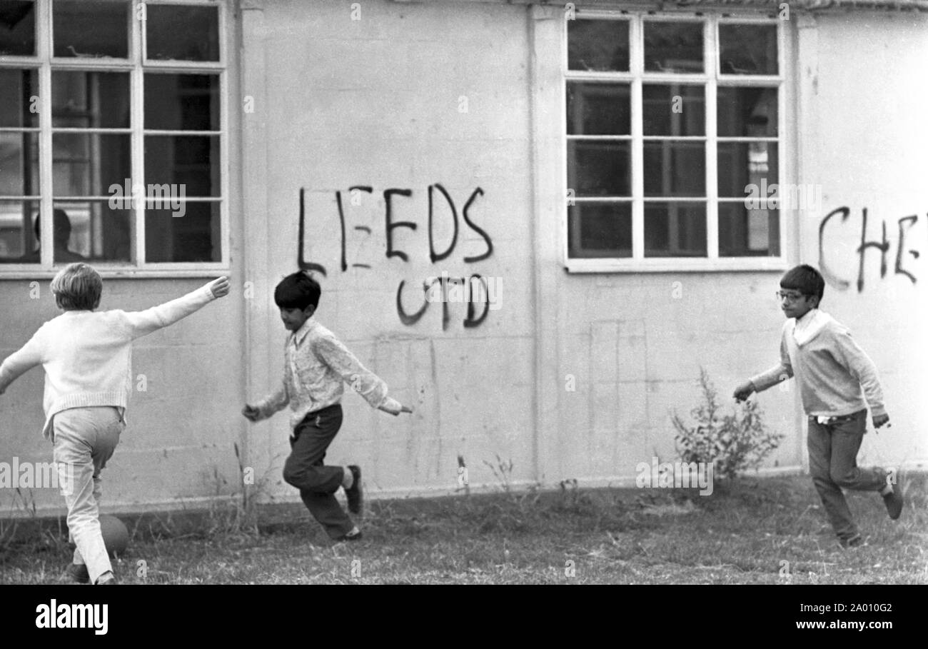 Southall, London 1972. Boys playing football by graffiti. After Idi Amin ordered 30,000 Asians out of Uganda with 90 days notice, those with British Passports headed to England. They were forced to leave their money, property and possessions behind. These images document life for some of those people as they settled in Southall, west of London. An insight into life 47 years ago for immigrants in the UK. Photo by Tony Henshaw Stock Photo
