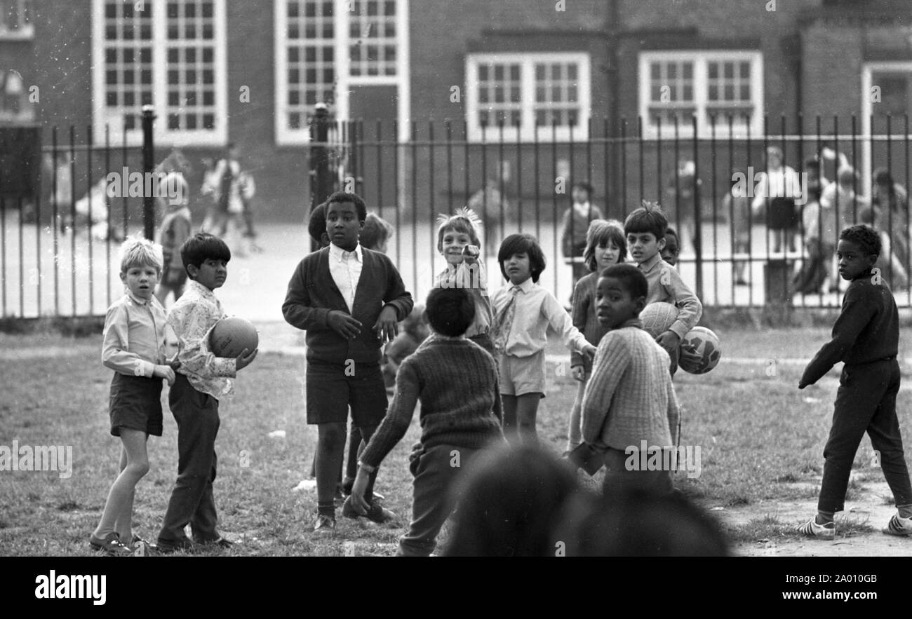 Southall, London 1972. Asian, black and white children playing at school. After Idi Amin ordered 30,000 Asians out of Uganda with 90 days notice, those with British Passports headed to England. They were forced to leave their money, property and possessions behind. These images document life for some of the people as they settled in Southall, west of London. An insight into life 47 years ago for immigrants in the UK. Photo by Tony Henshaw Stock Photo