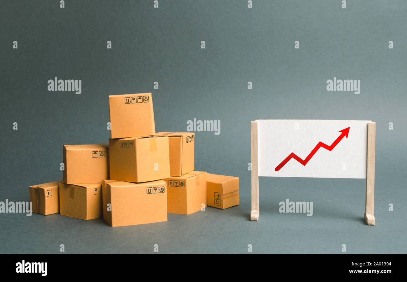 Plenty of cardboard boxes and whiteboard with red positive trend chart. Increasing consumer demand. rate growth of production of goods and products, i Stock Photo