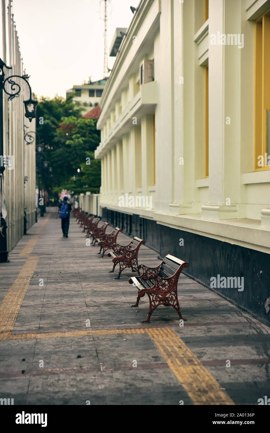 A row of Classic Wooden bench with iron black legs on a stone sidewalk city Stock Photo