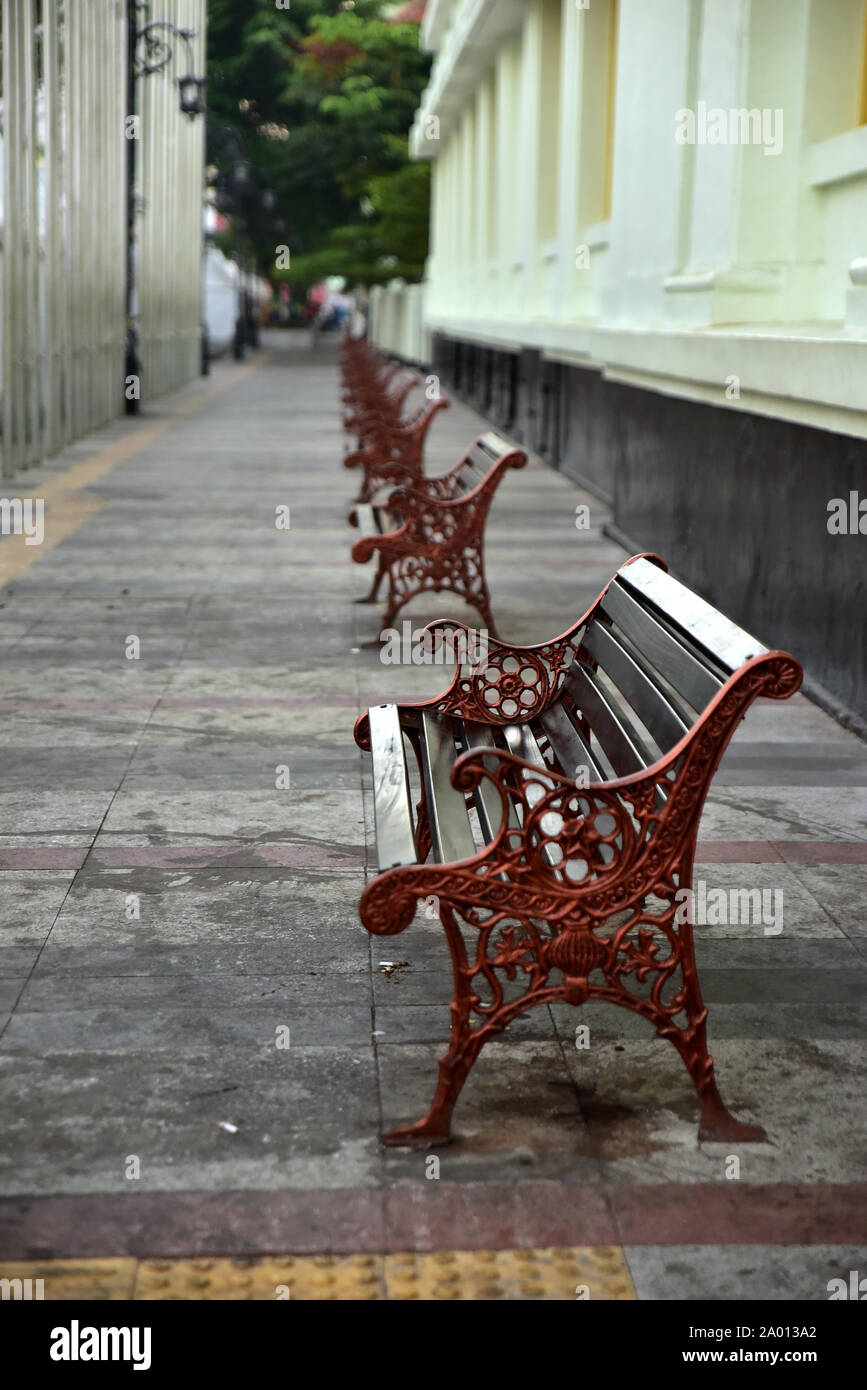 A row of Classic Wooden bench with iron black legs on a stone sidewalk city Stock Photo