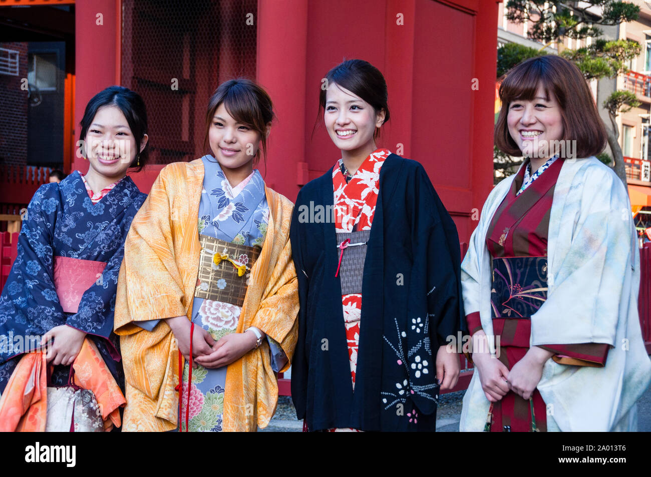 Warm smiles from four Japanese women dressed in colorfully rich Kimonos