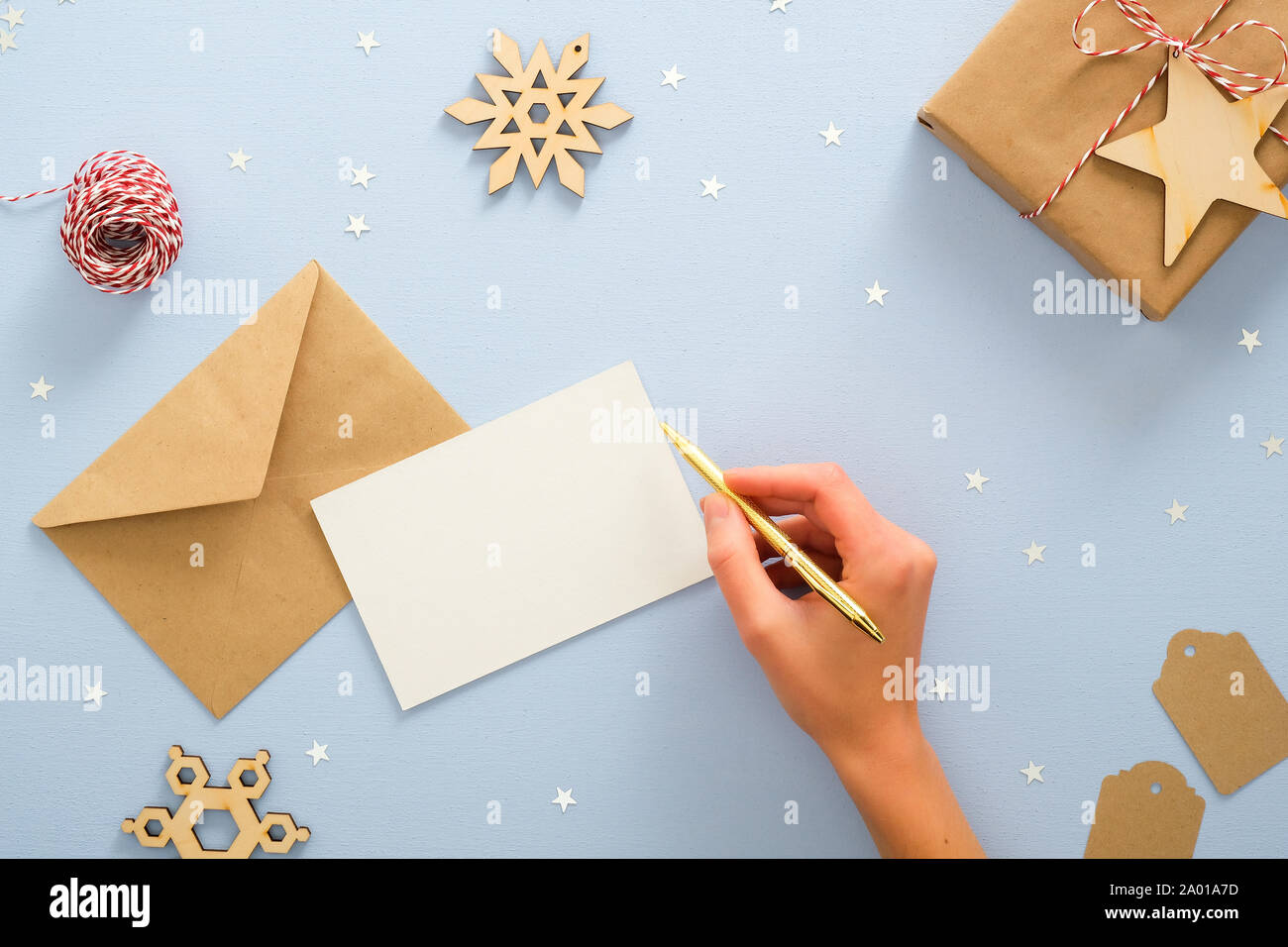 Female Hand Writing Letter To Santa Claus Over Blue