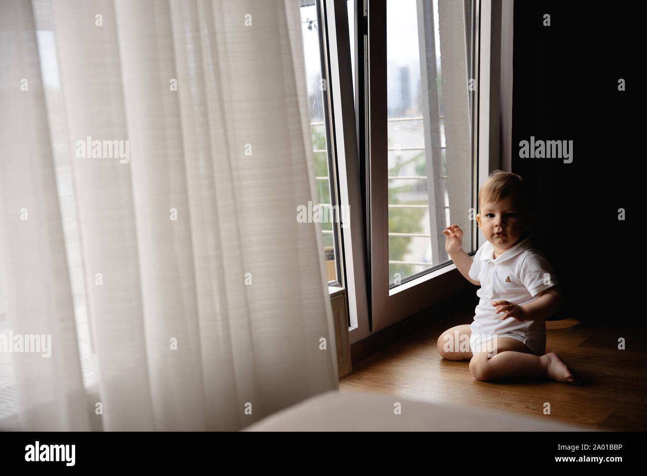 Young blonde mother having quality time with her baby boy son at family home flat - Wearing black budoir dress costume sleeping gown Stock Photo