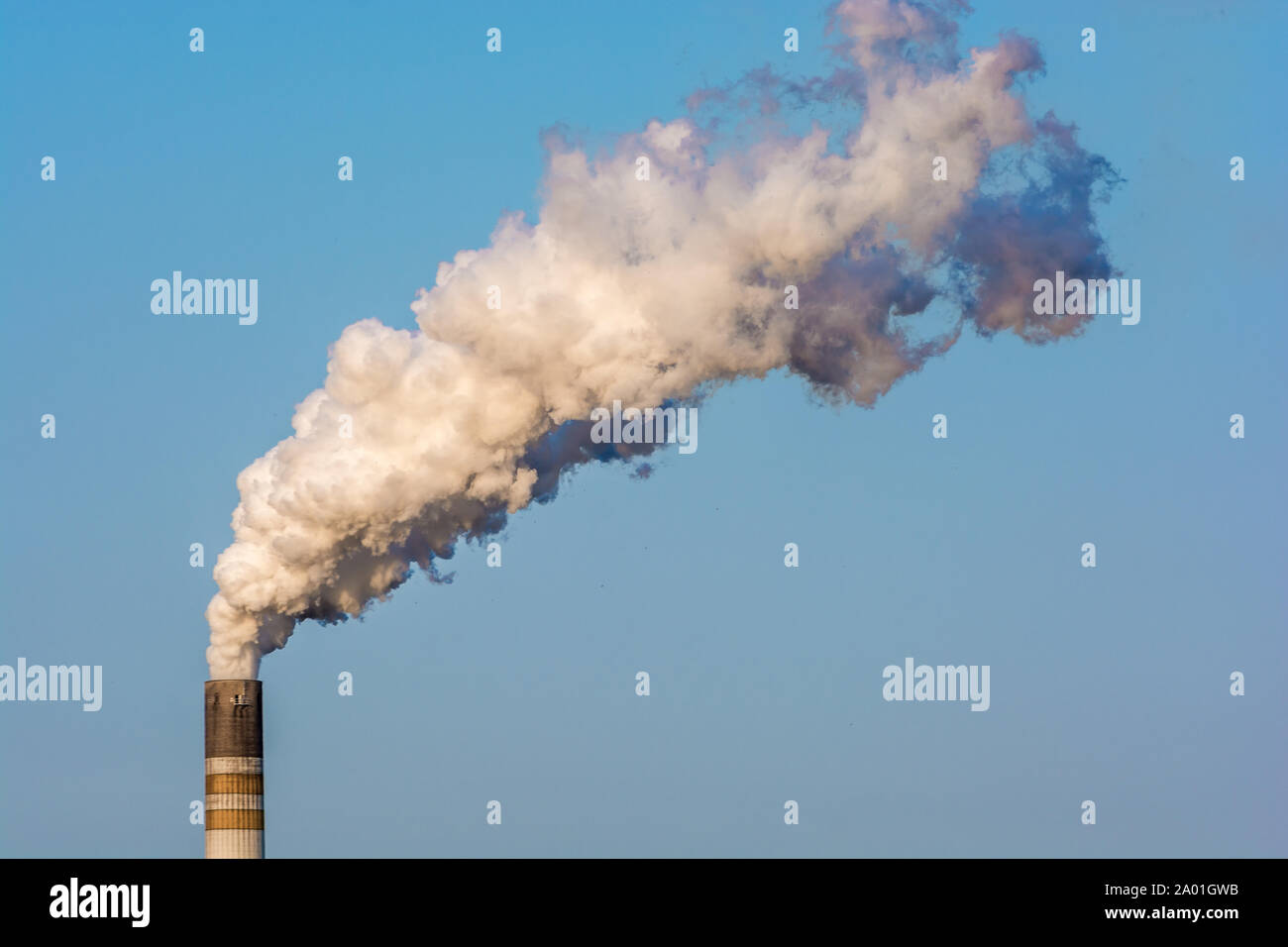Highly smoking chimney against a blue sky Stock Photo
