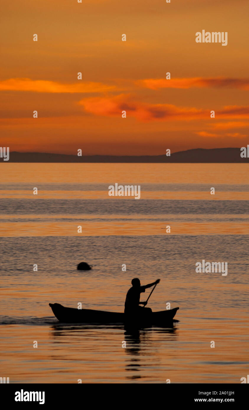 Evening silhouette of a fisherman in a boat near Cape Maclear, Lake Malawi Stock Photo