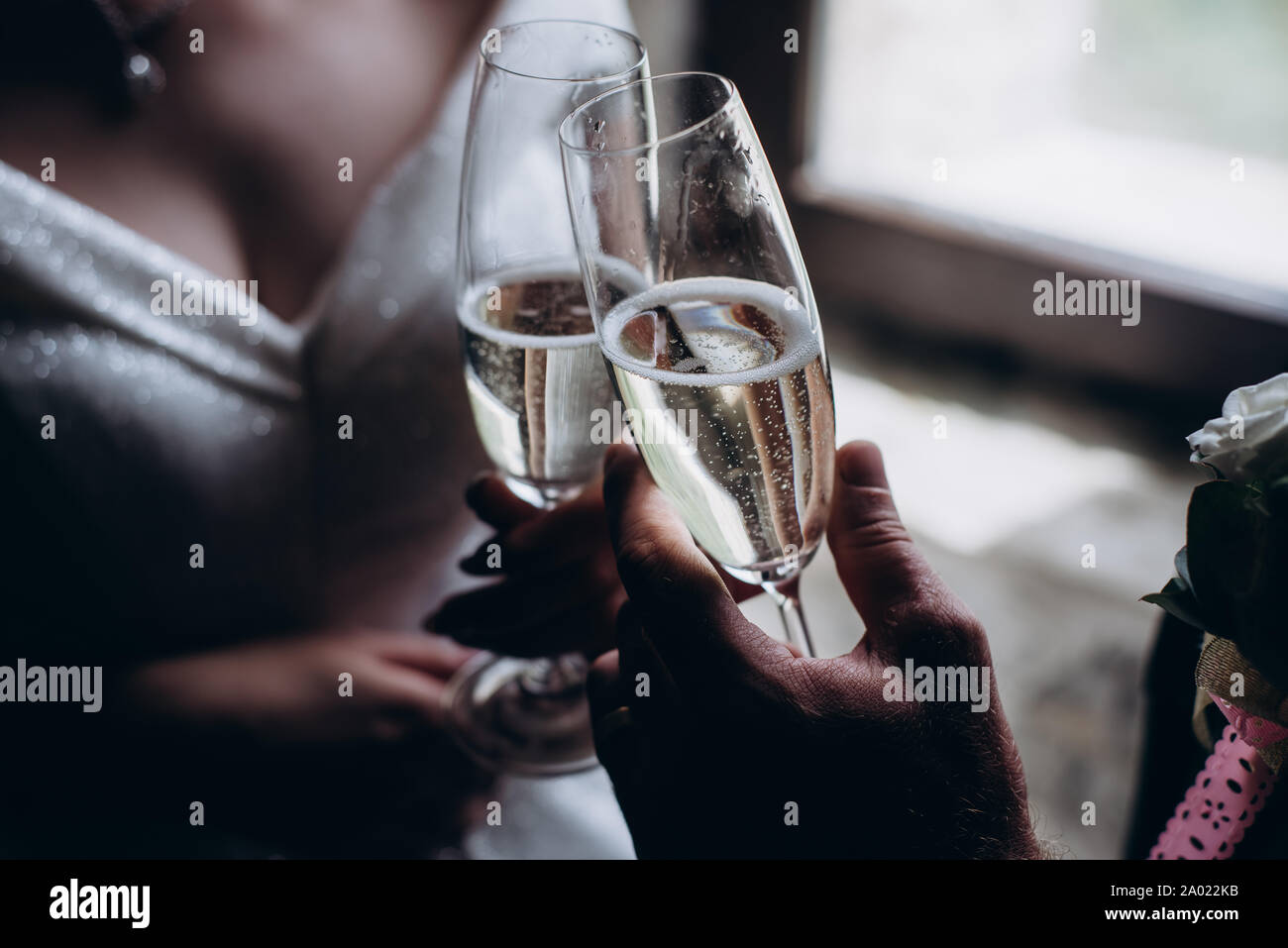 horizontal image of a married couple toasting champagne glasses at wedding party hands bride and groom clinking glasses at wedding reception 2A022KB