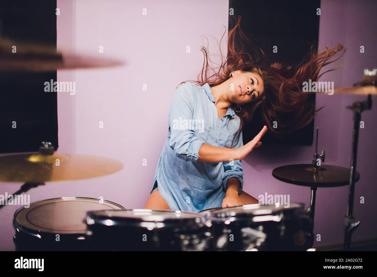 Silhouette of female drummer performing on stage with dramatic concert lighting