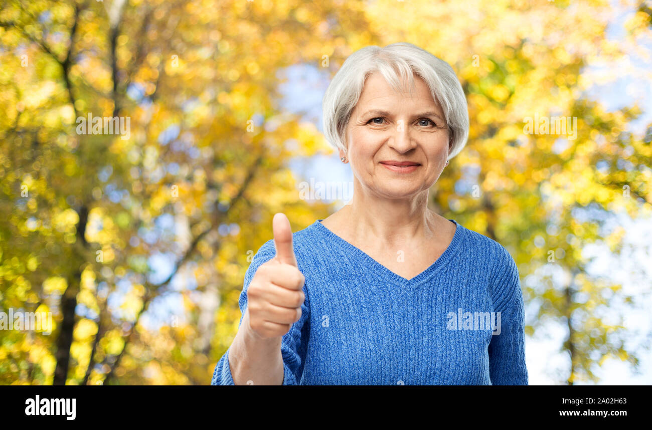 senior woman r showing thumbs up in autumn park Stock Photo
