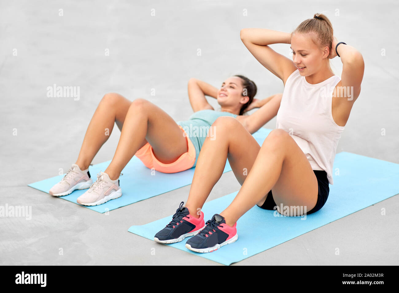 women training and doing sit-ups outdoors Stock Photo