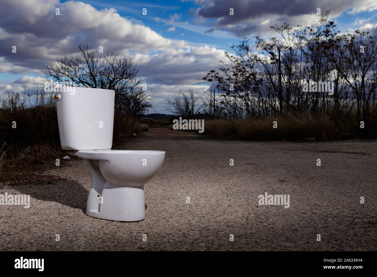 White toilet dumped on a rural road in Spain Stock Photo