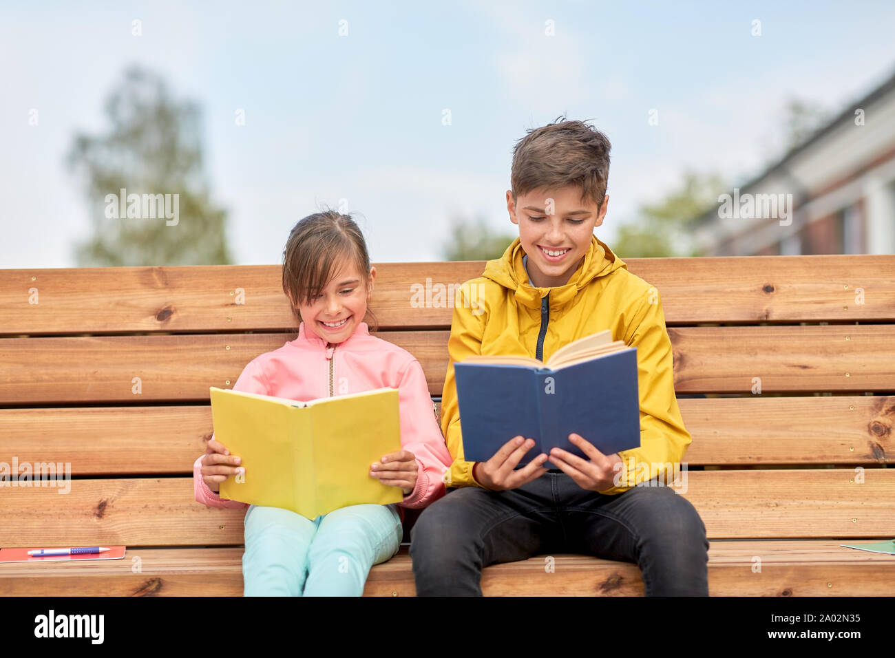 school children reading books sitting on bench Stock Photo Alamy