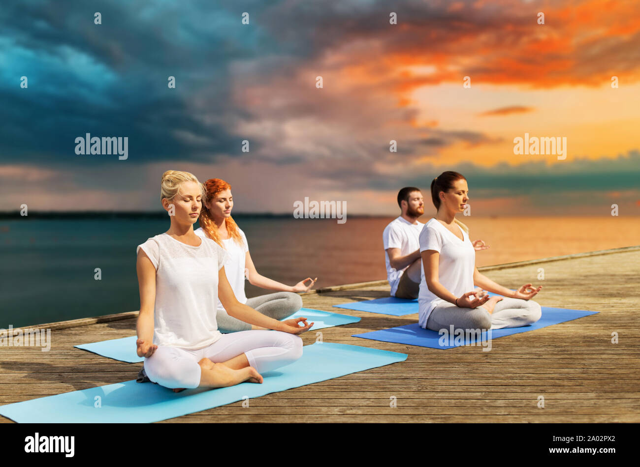 people meditating in yoga lotus pose outdoors Stock Photo