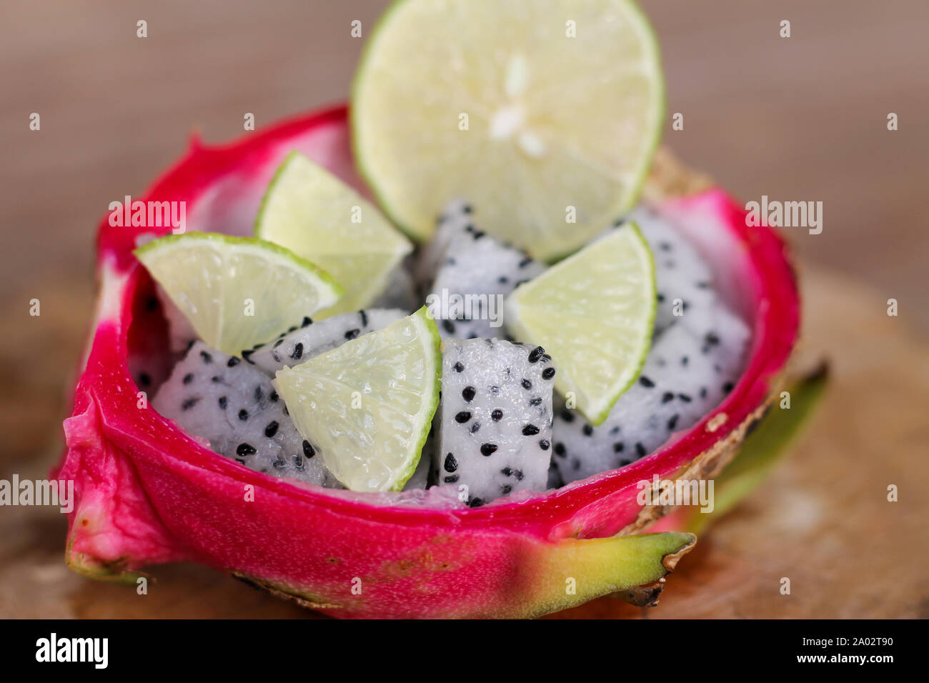 Dragon fruit sliced and lime sliced in a haft of dragon fruit peel on old wooden table background. Stock Photo