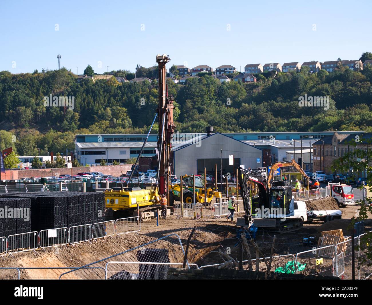 Pile driver and other construction machines and people working on a building site in Huddersfield Yorkshire Engkand Stock Photo