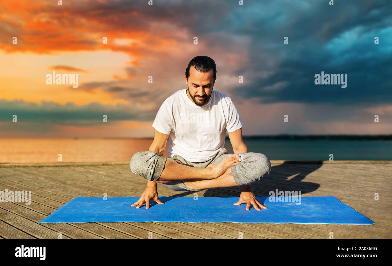 man making yoga in scale pose outdoors Stock Photo
