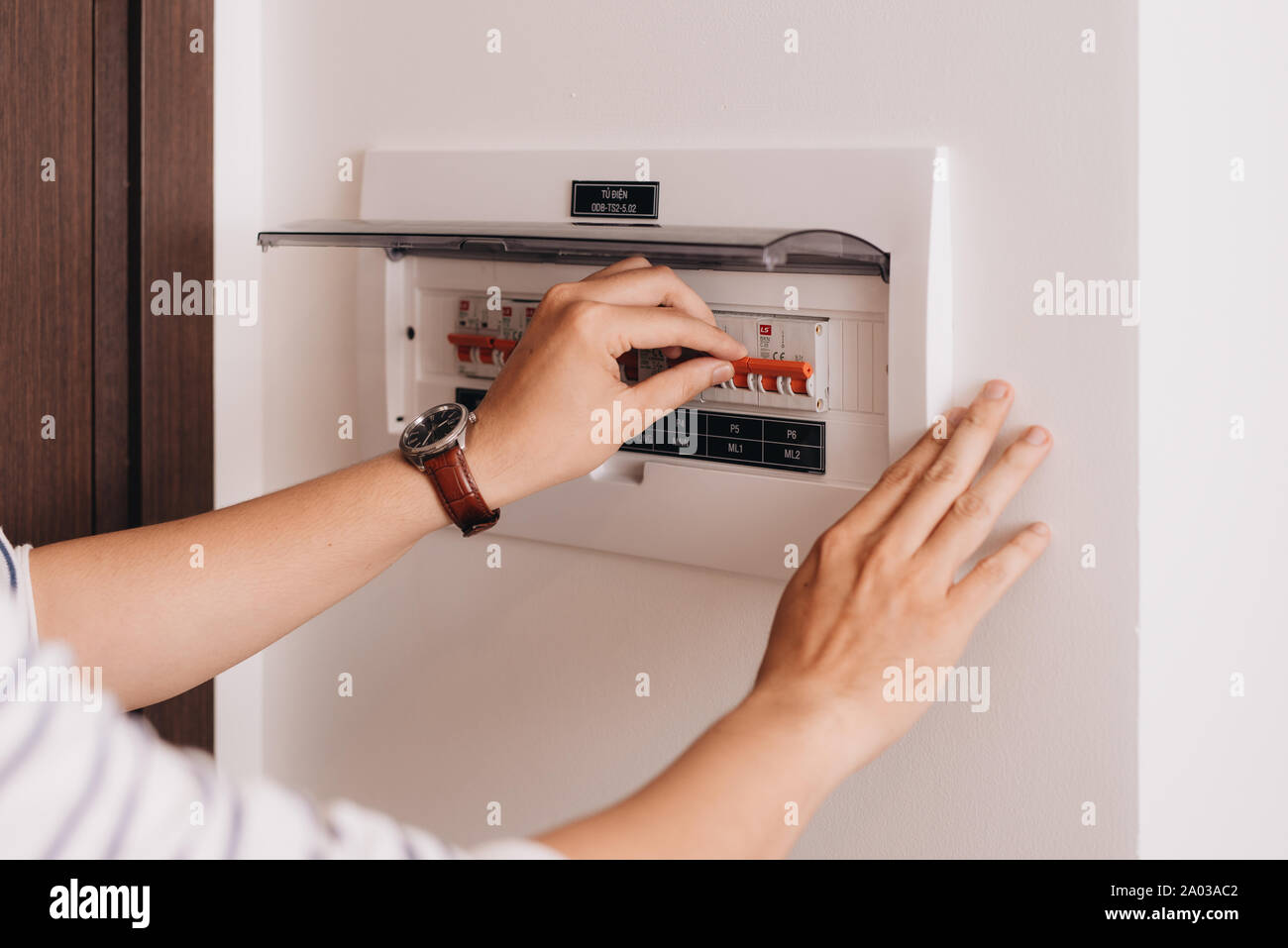 Circuit breaker board displays many switches. A finger is about to turn