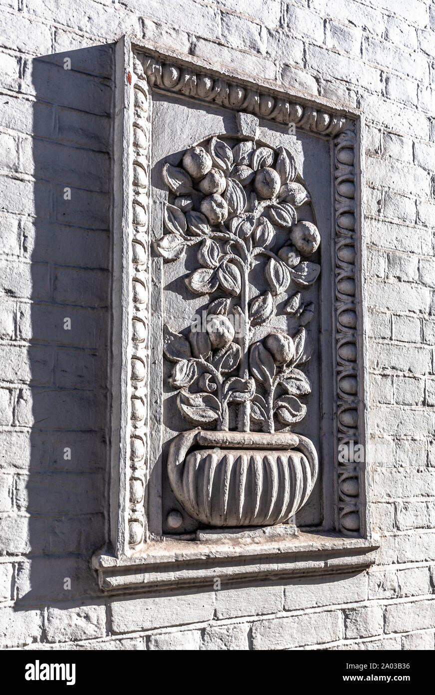 A framed relief sculpture of a plant pot on a brick wall, London, England, UK. Stock Photo
