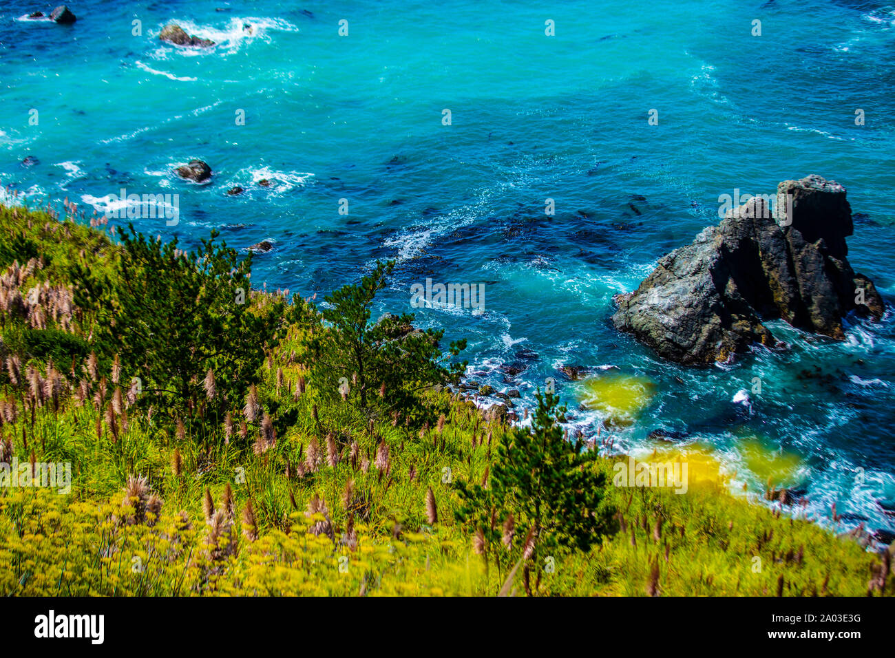 Der pazifische Ozean am Küstenabschnitt Big Sur in Kalifornien. Türkises Wasser, Steilfelsen und Blumenwiese bilden einen schönen Kontrast. Stock Photo