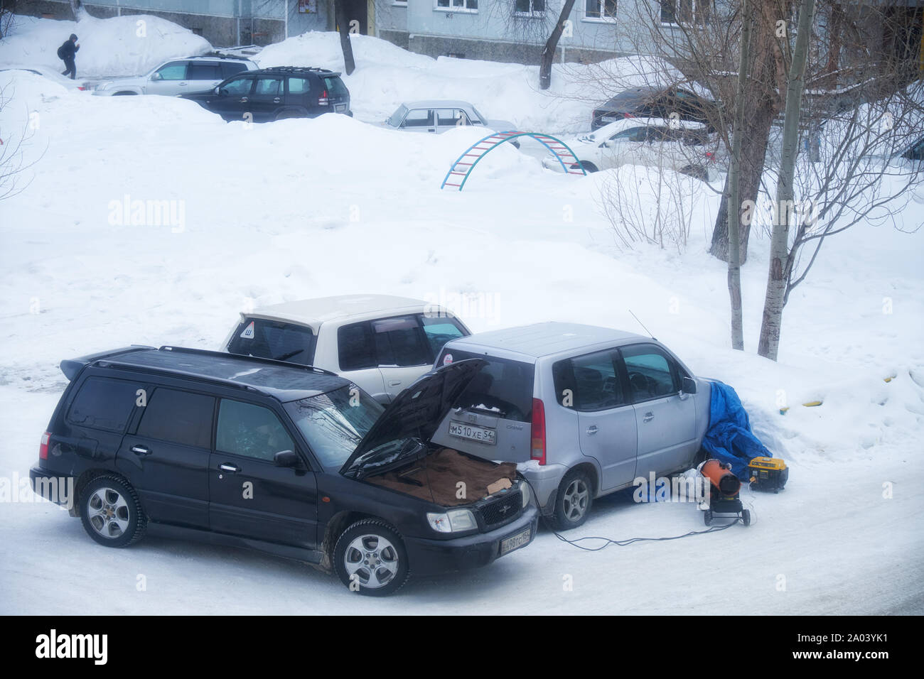 NOVOSIBIRSK, RUSSIA - FEBRUARY 01, 2019:  Frosts in Siberian town Novosibirsk.  Frozen cars under the snow in the yard on parking.Technical service is Stock Photo