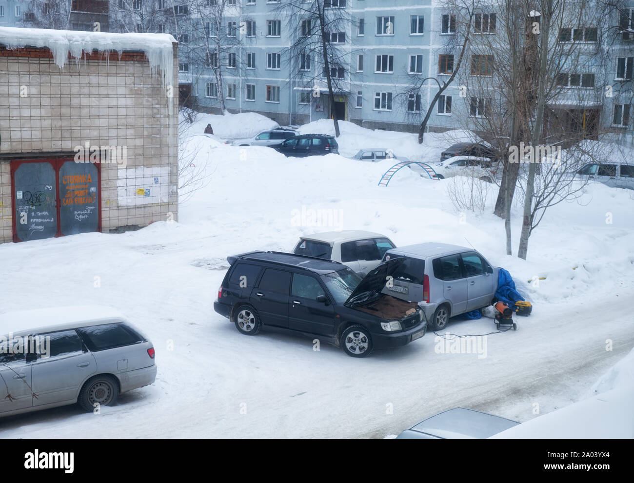 NOVOSIBIRSK, RUSSIA - FEBRUARY 01, 2019:  Frosts in Siberian town Novosibirsk.  Frozen cars under the snow in the yard on parking.Technical service is Stock Photo