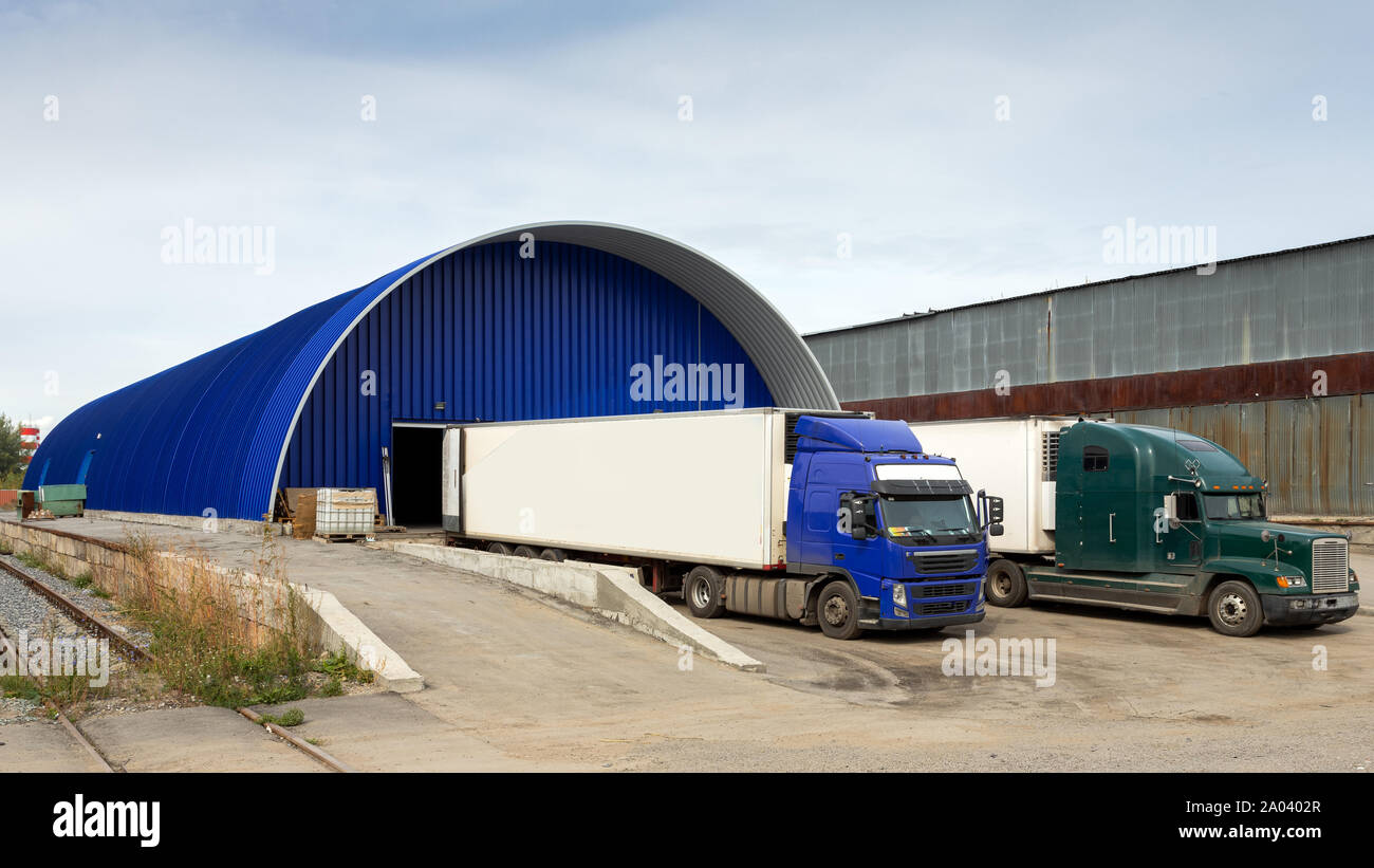 Delivering and supply concept image. Trucks loading at facility in the