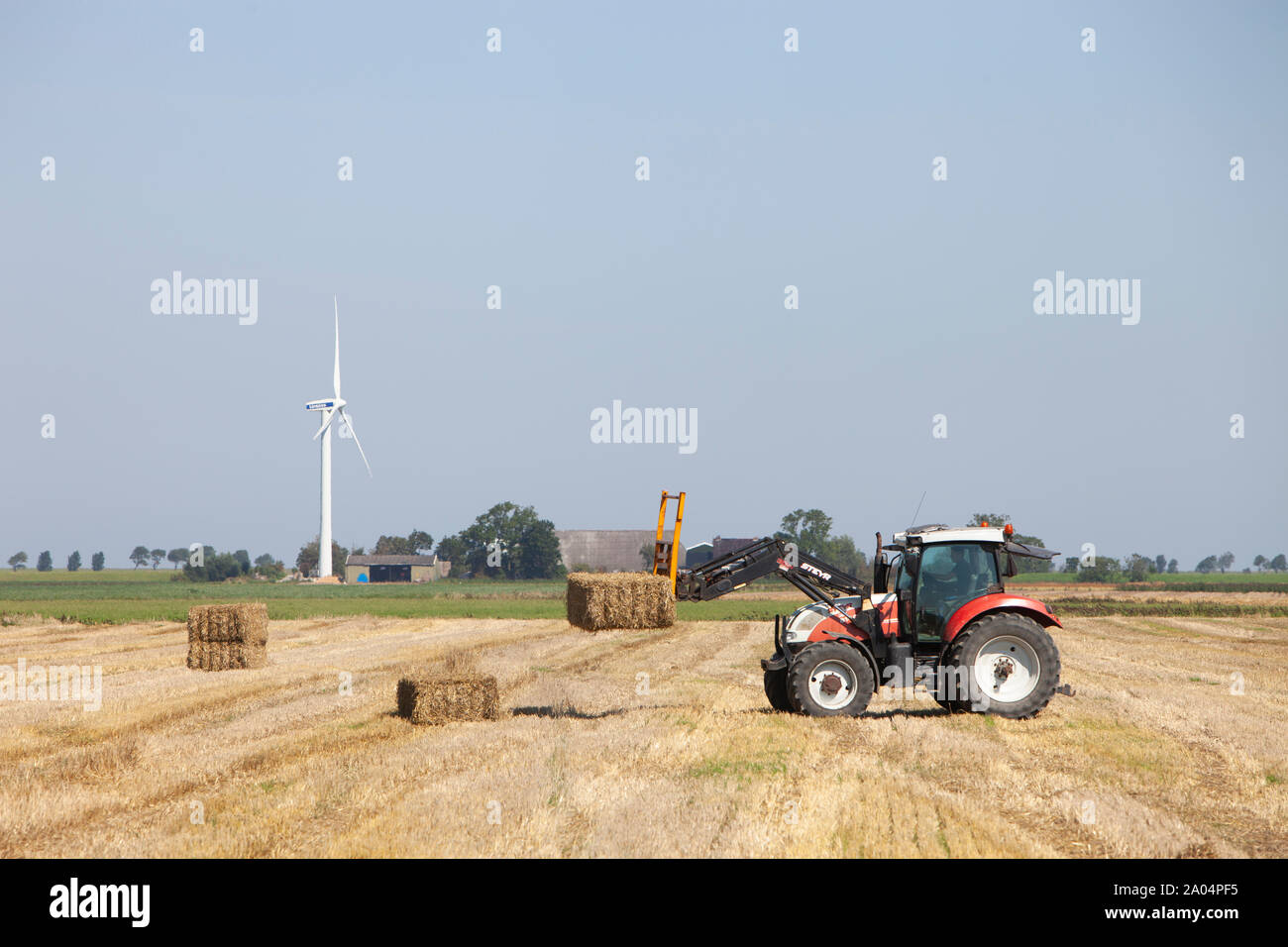 farmer in tractor busy collecting hay bales with tractor in dutch province of groningen Stock Photo