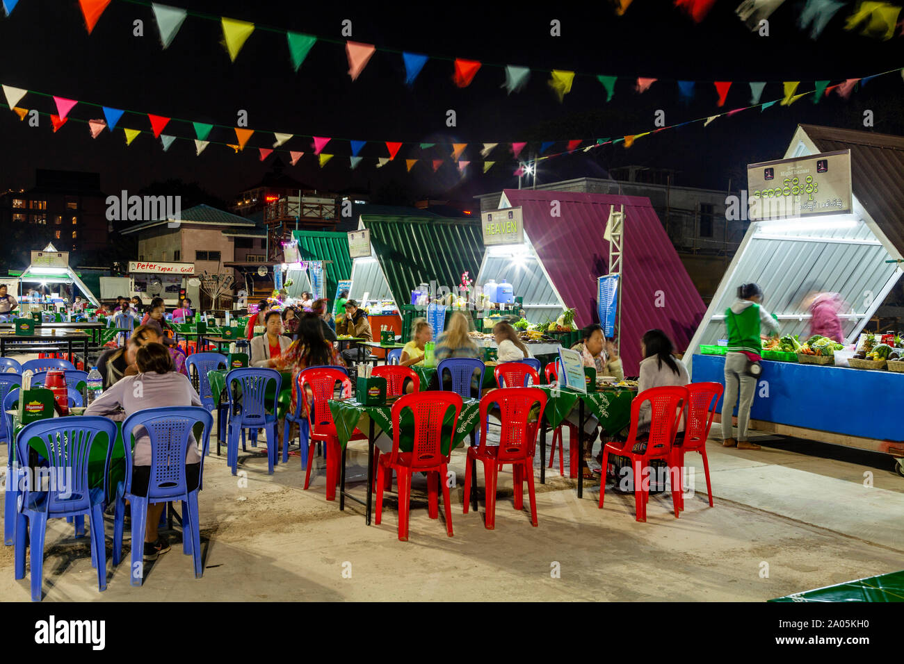 Local People and Tourists Eating Street Food At Tables In The Night Market, Nyaung Shwe, Lake Inle, Shan State, Myanmar. Stock Photo