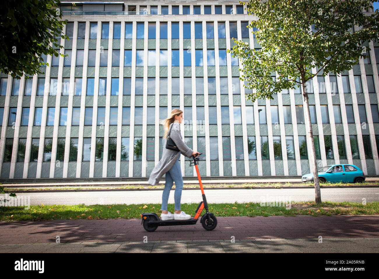 woman on a electric scooter of the company circ on the banks of the river Rhine in front of the Institute for Economic Research, Cologne, Germany.   F Stock Photo