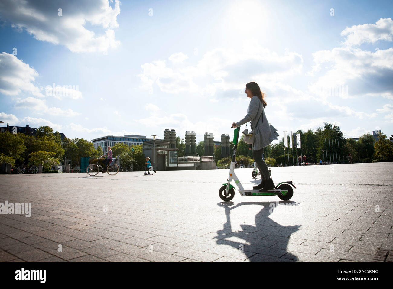 woman on a electric scooter of the company Lime in the Mediapark, Cologne, Germany.   Frau auf Elektroscooter des Anbieters Lime im Mediapark, Koeln, Stock Photo