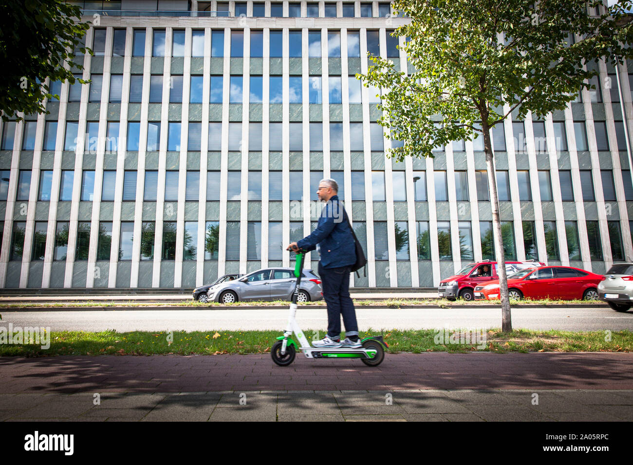 man on a electric scooter of the company Lime on the banks of the river  Rhine in front of the Institute for Economic Research, Cologne, Germany.  Churc Stock Photo - Alamy
